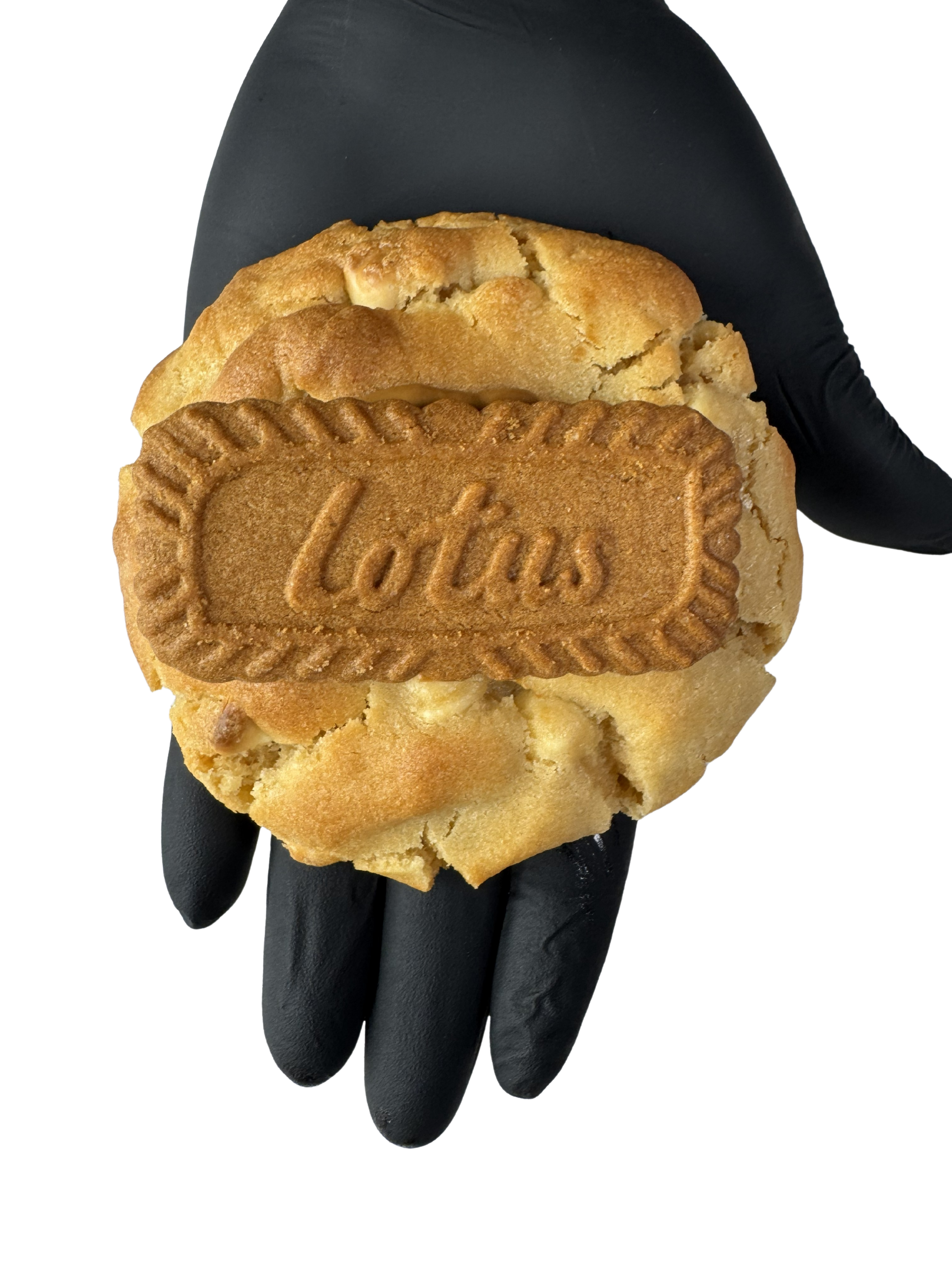 A hand holding a Biscoff Stuffed cookie, mid-bite, melted spread oozing from the centre